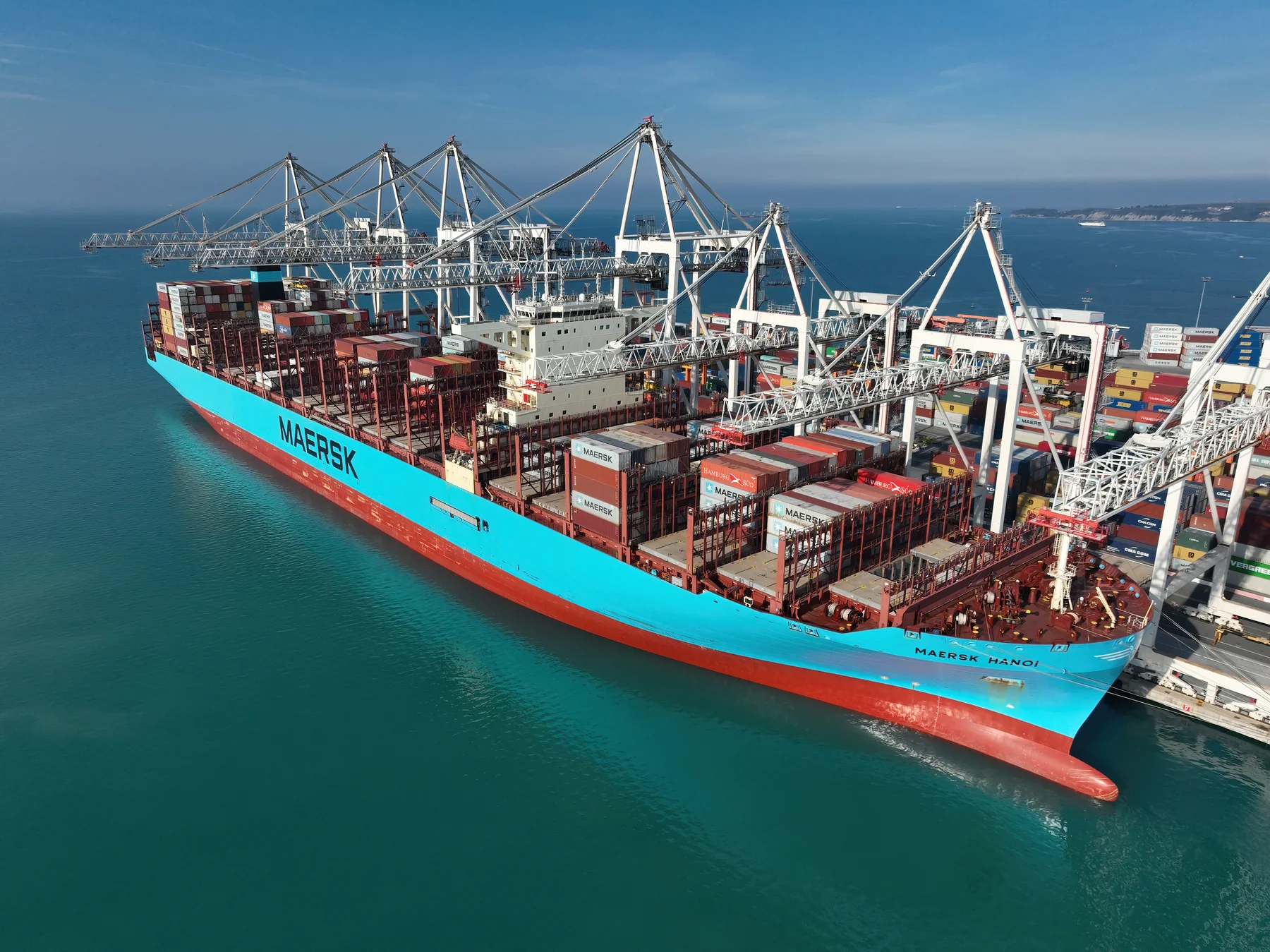 A container ship alongside cargo cranes at a commercial port